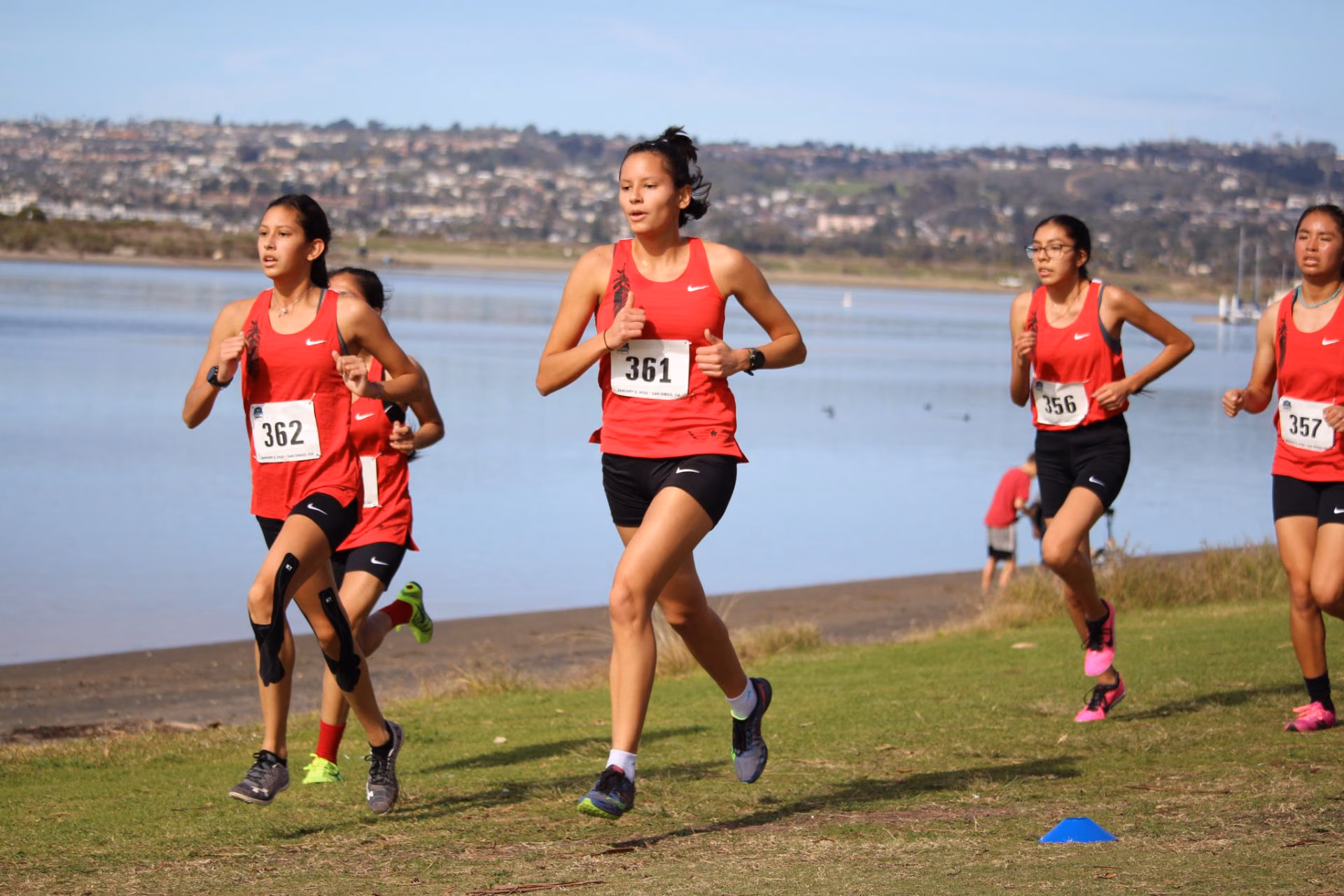 Wings National Team runners racing in red uniforms along a waterfront course